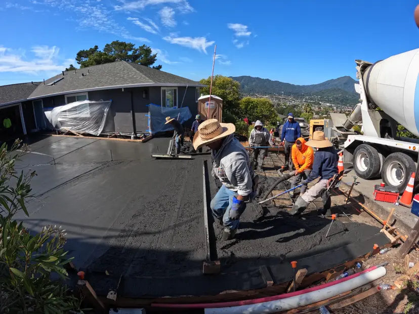 Crew finishing a fresh concrete pour with the mixer truck alongside