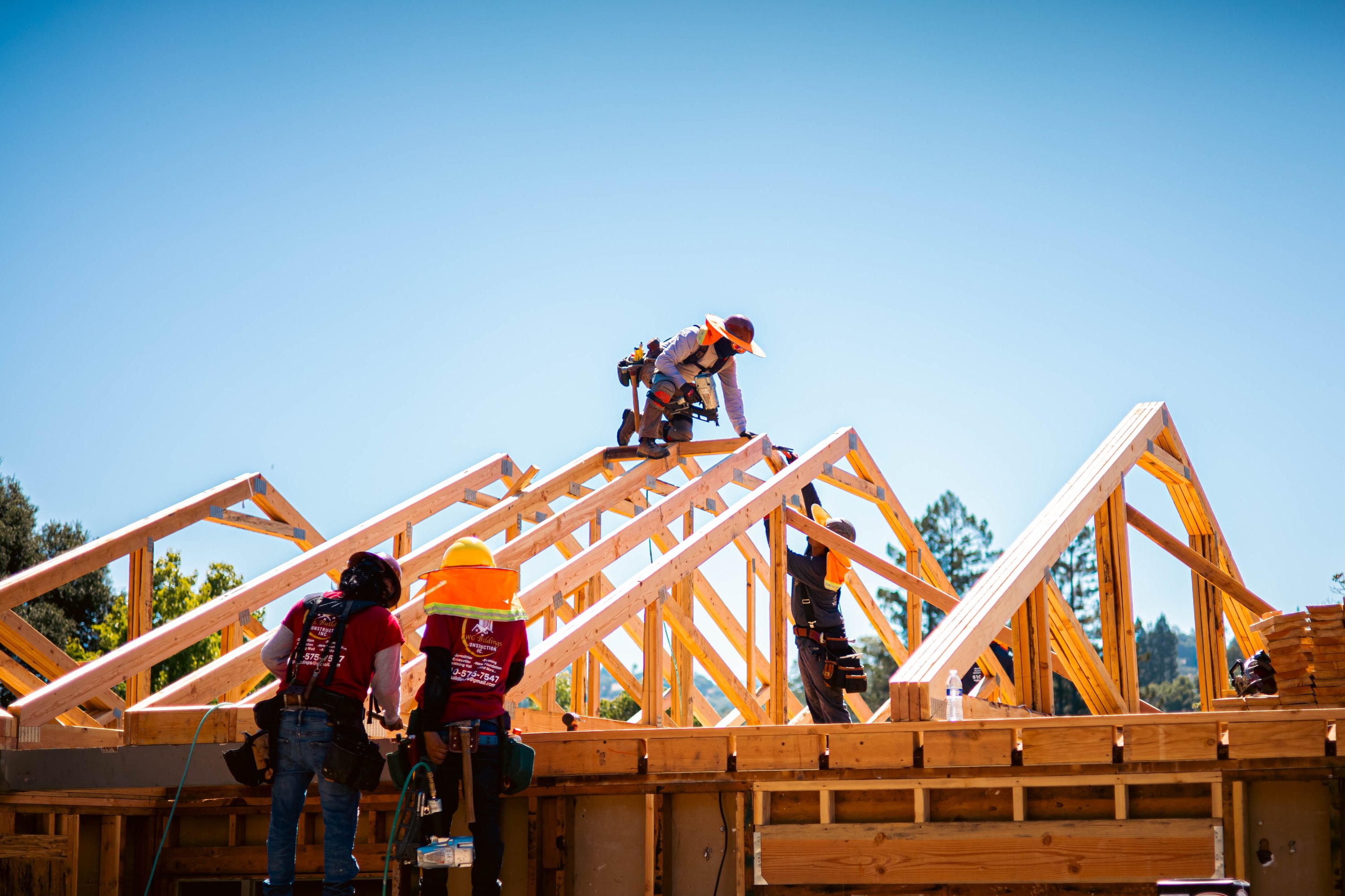 WG crew setting roof trusses on a new home under a clear sky